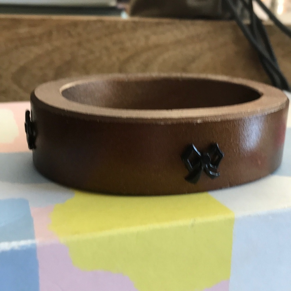 Brown wooden cuff with small black bows around It.